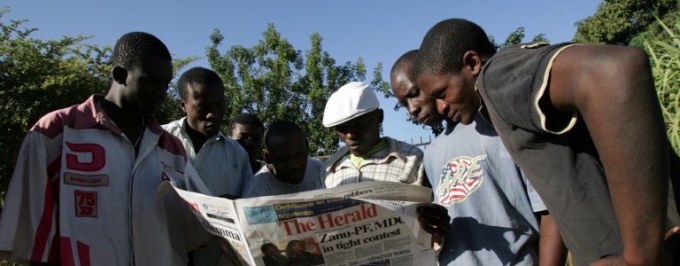 Zimbabweans reading a newspaper copy